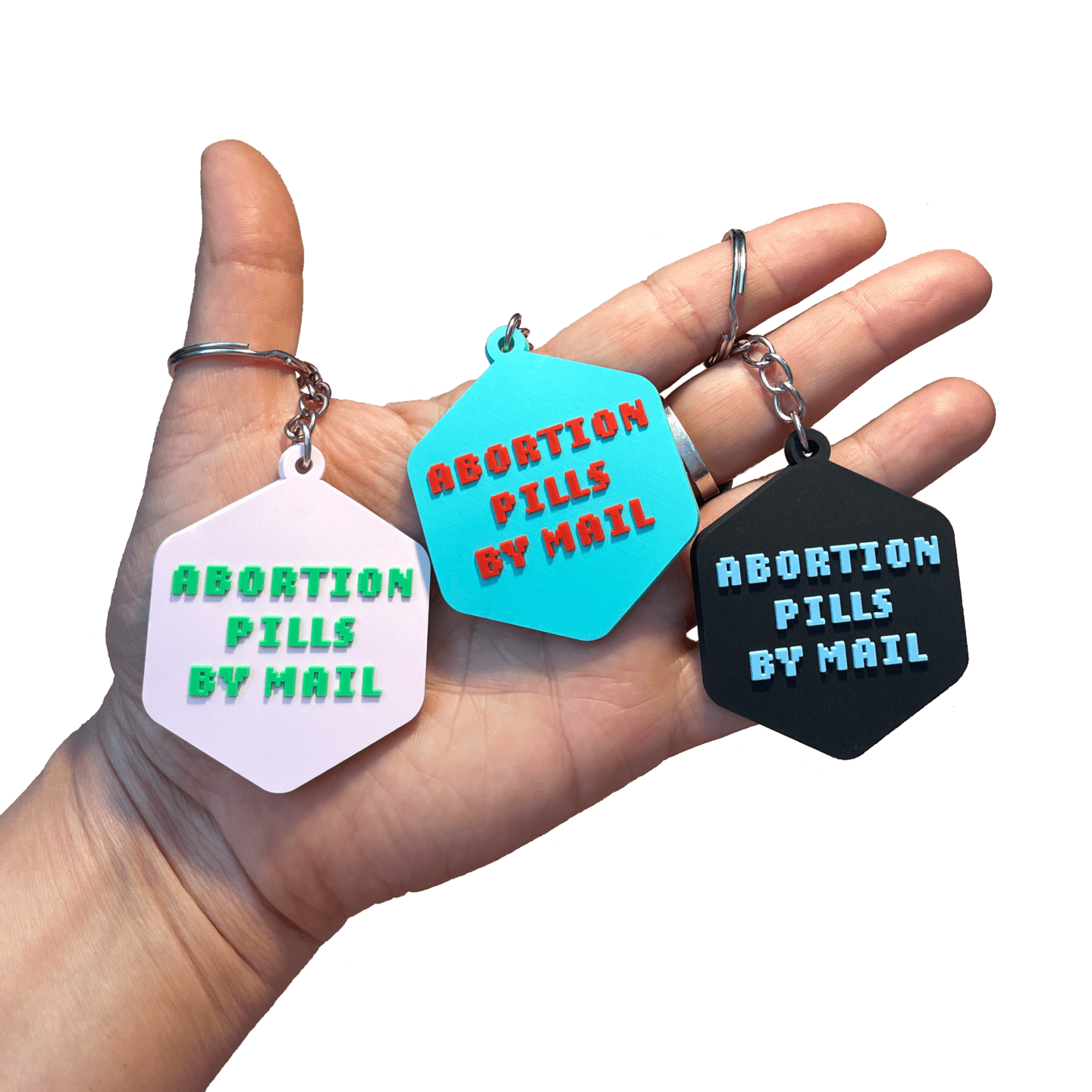 Hand holding a pink, blue, and black keychain that says abortion pills by mail