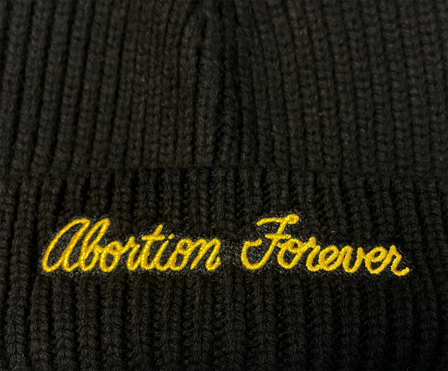Black knit beanie with Abortion Forever embroidered in gold thread on the cuff