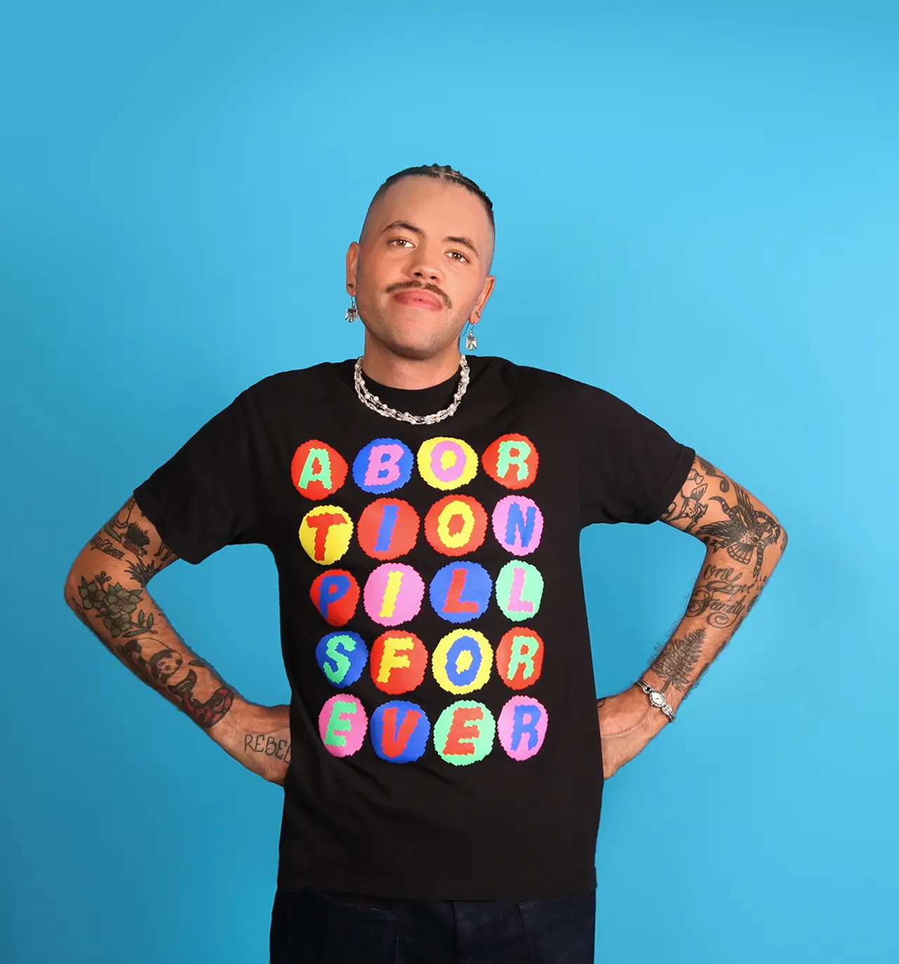 Black tee shirt with multicolored graphic spelling out ABORTION PILLS FOREVER