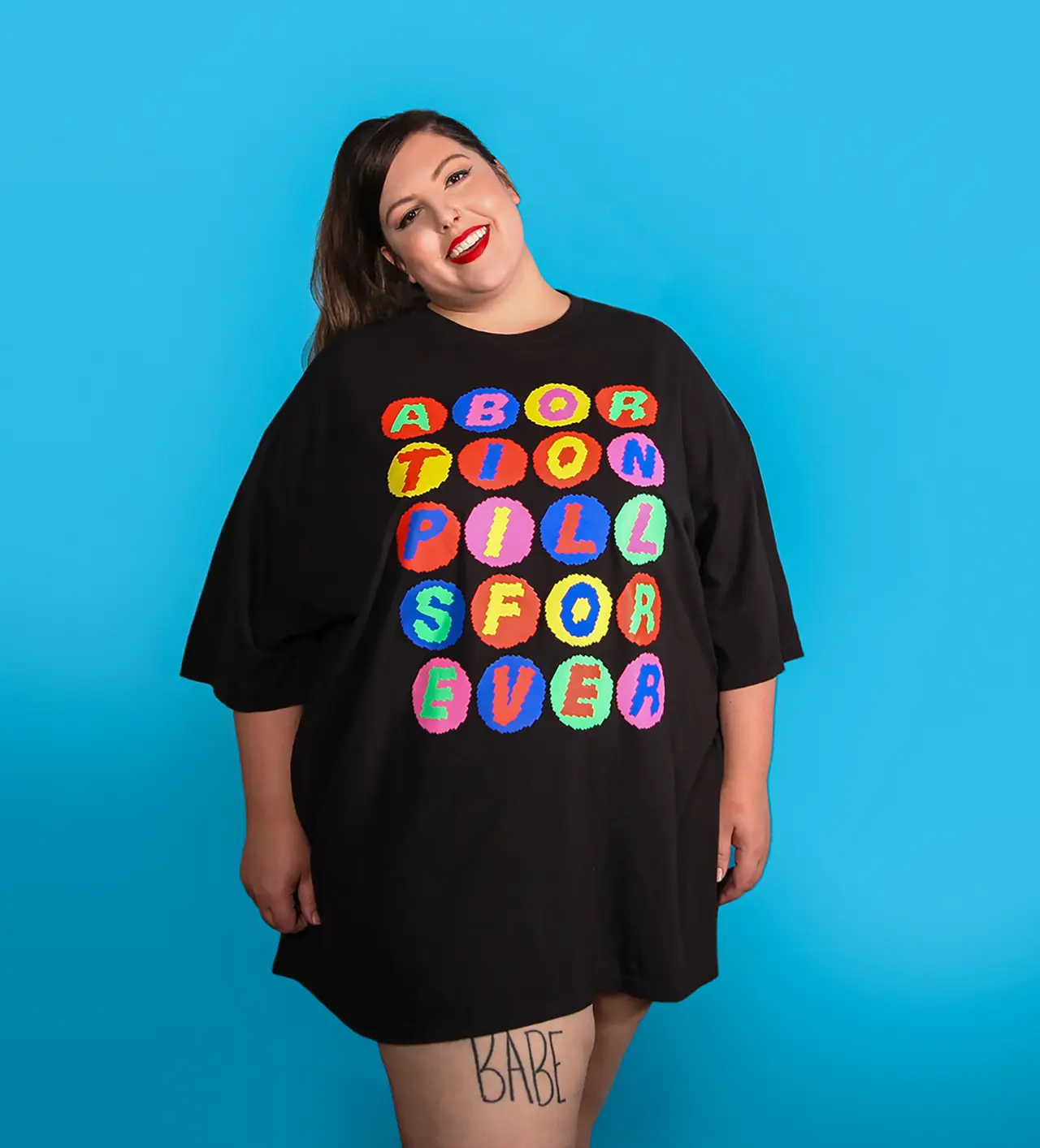 Black tee shirt with multicolored graphic spelling out ABORTION PILLS FOREVER