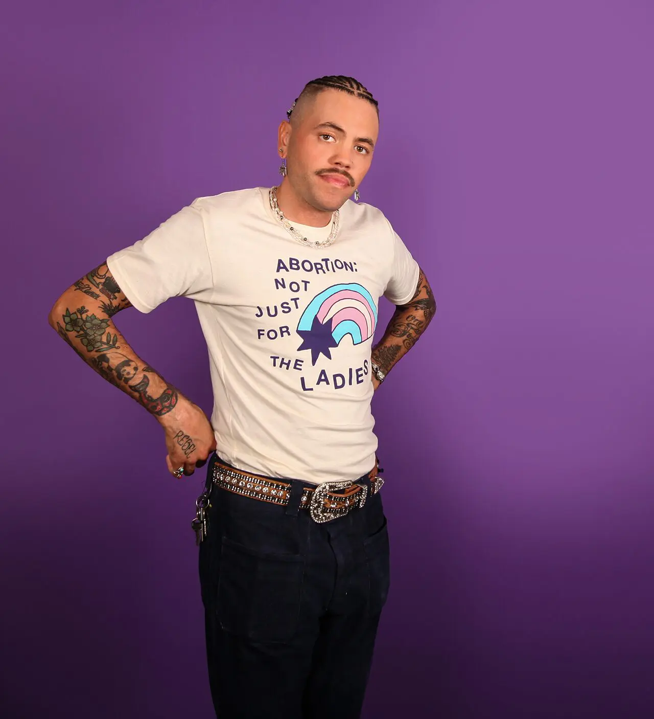 Model wearing a cream colored tee shirt with dark blue ink that reads 