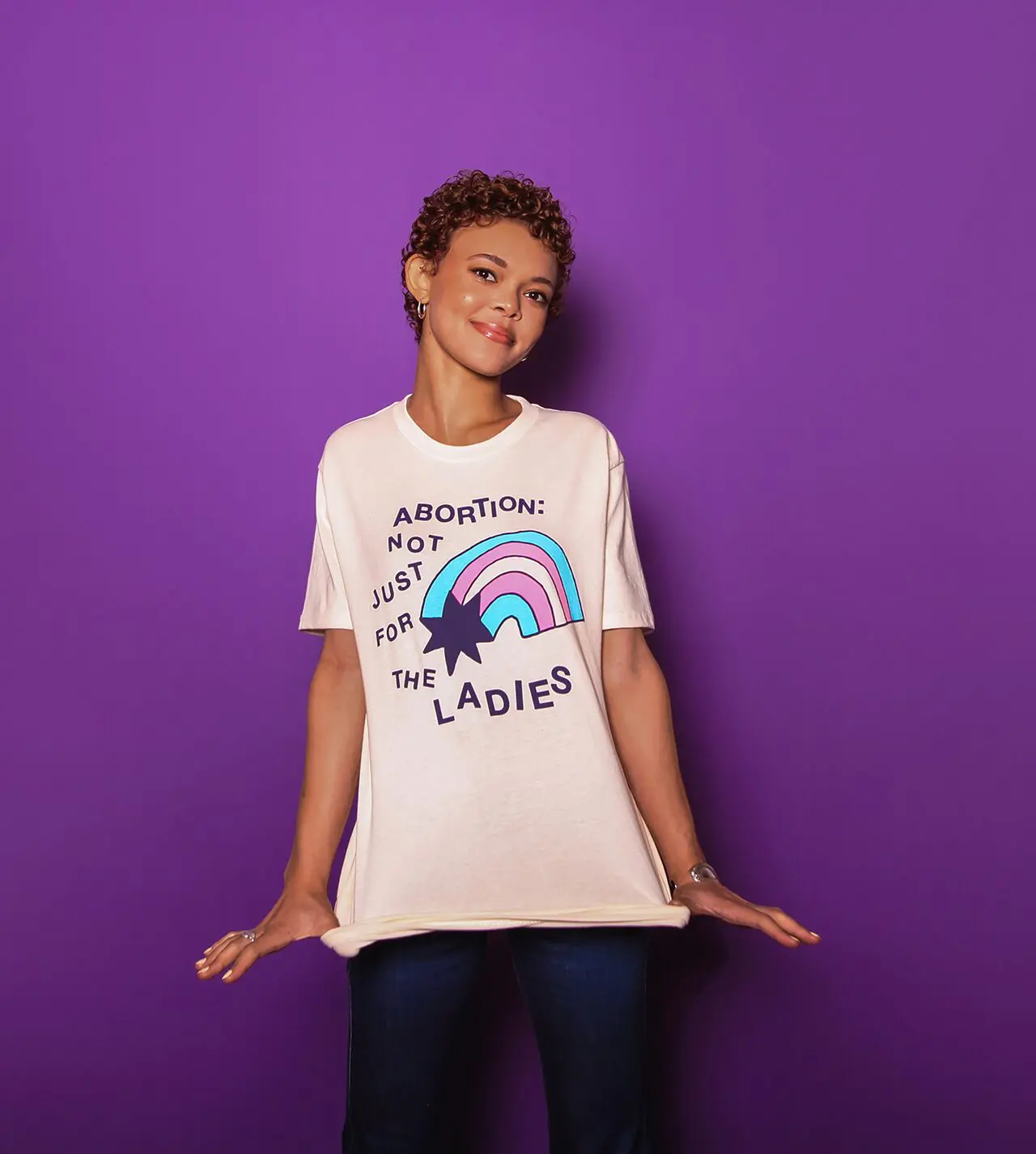 Model wearing a cream colored tee shirt with dark blue ink that reads 